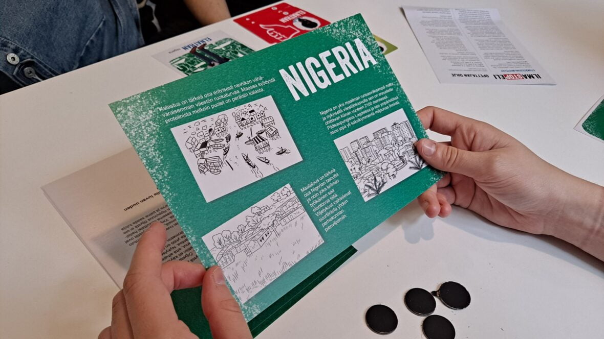 Kädet pitävät korttia, jossa otsikkona Nigeria ja tekstiä ja kuvia.